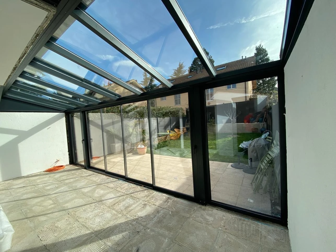 Originale Projektaufnahme eines Glasanbaus mit Glasdach und Schiebefenstern
